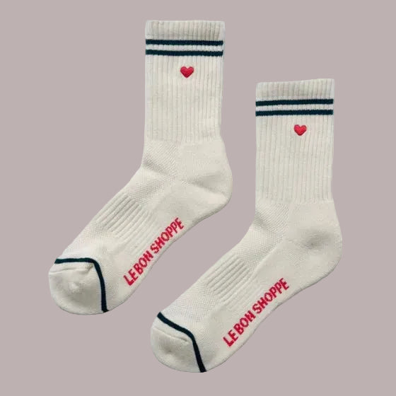 White socks with red hearts and 'Le Bon Shoppe' branding on a pink background