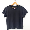Black t-shirt on a wooden hanger against a white background