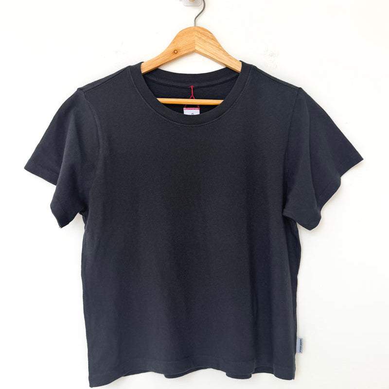 Black t-shirt on a wooden hanger against a white background