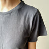 Person wearing a plain dark gray t-shirt by Le Bon Shoppe against a neutral background