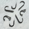 A collection of iron wall hooks with an uncoated matte finish, displayed on a marble surface.