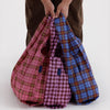 Plaid bags in pink, blue, and houndstooth pattern held by a person on a white background