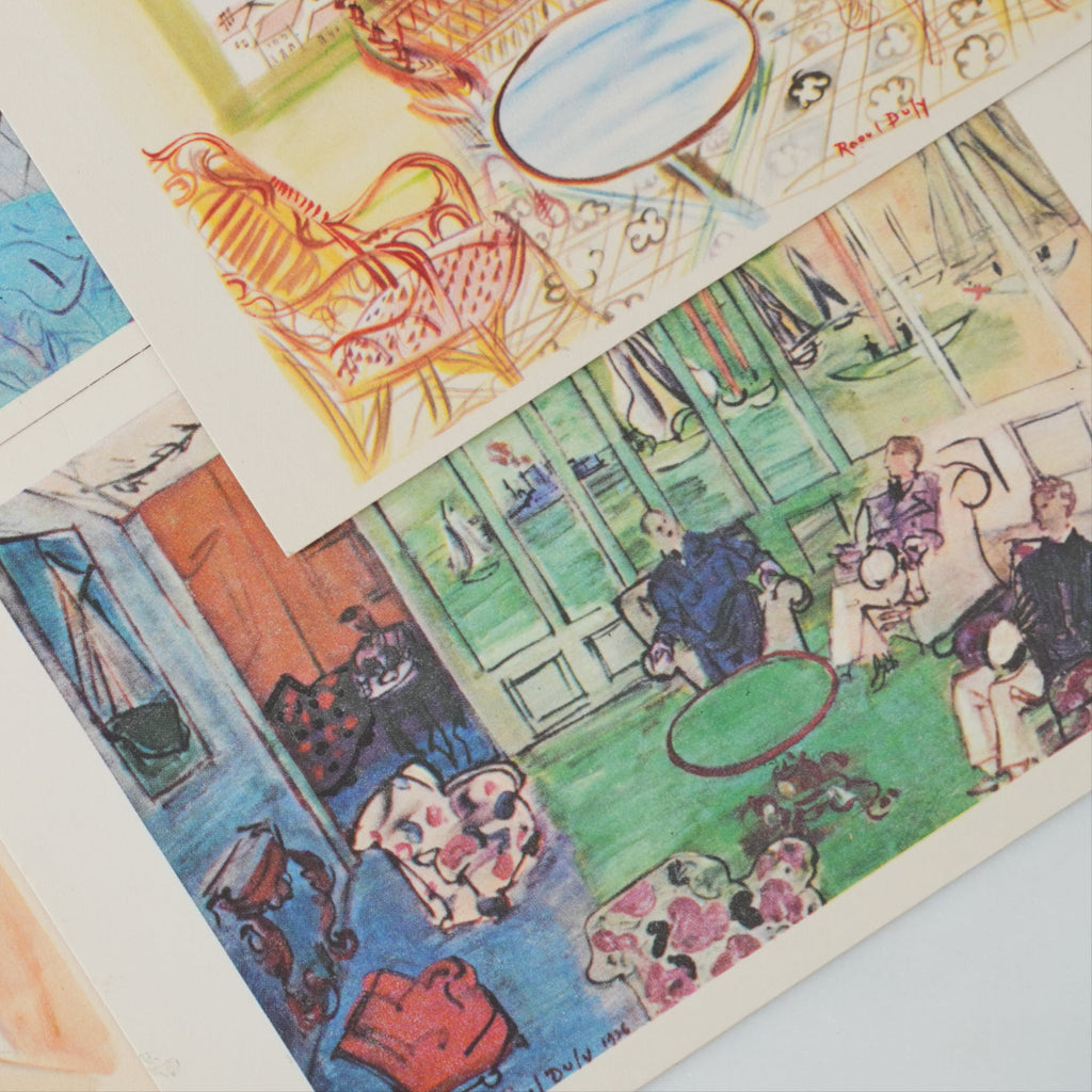 Collection of colorful illustrated vintage Dufy postcards on a white surface