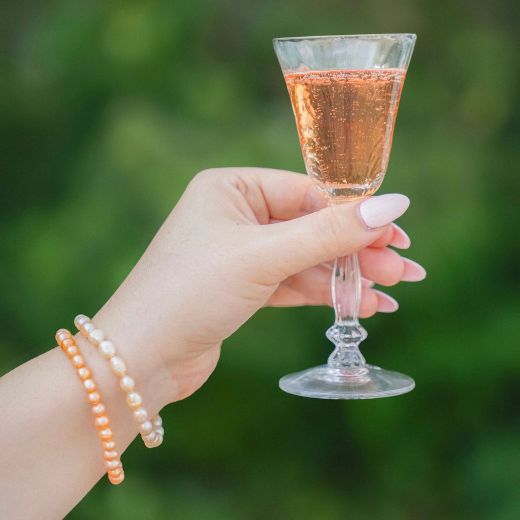 Pearl Bracelets on Wrists Holding Cocktail Glass