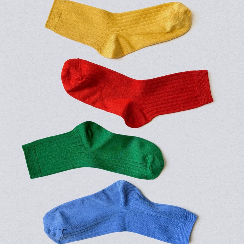 Four colorful socks (yellow, red, green, blue) arranged on a light gray background.