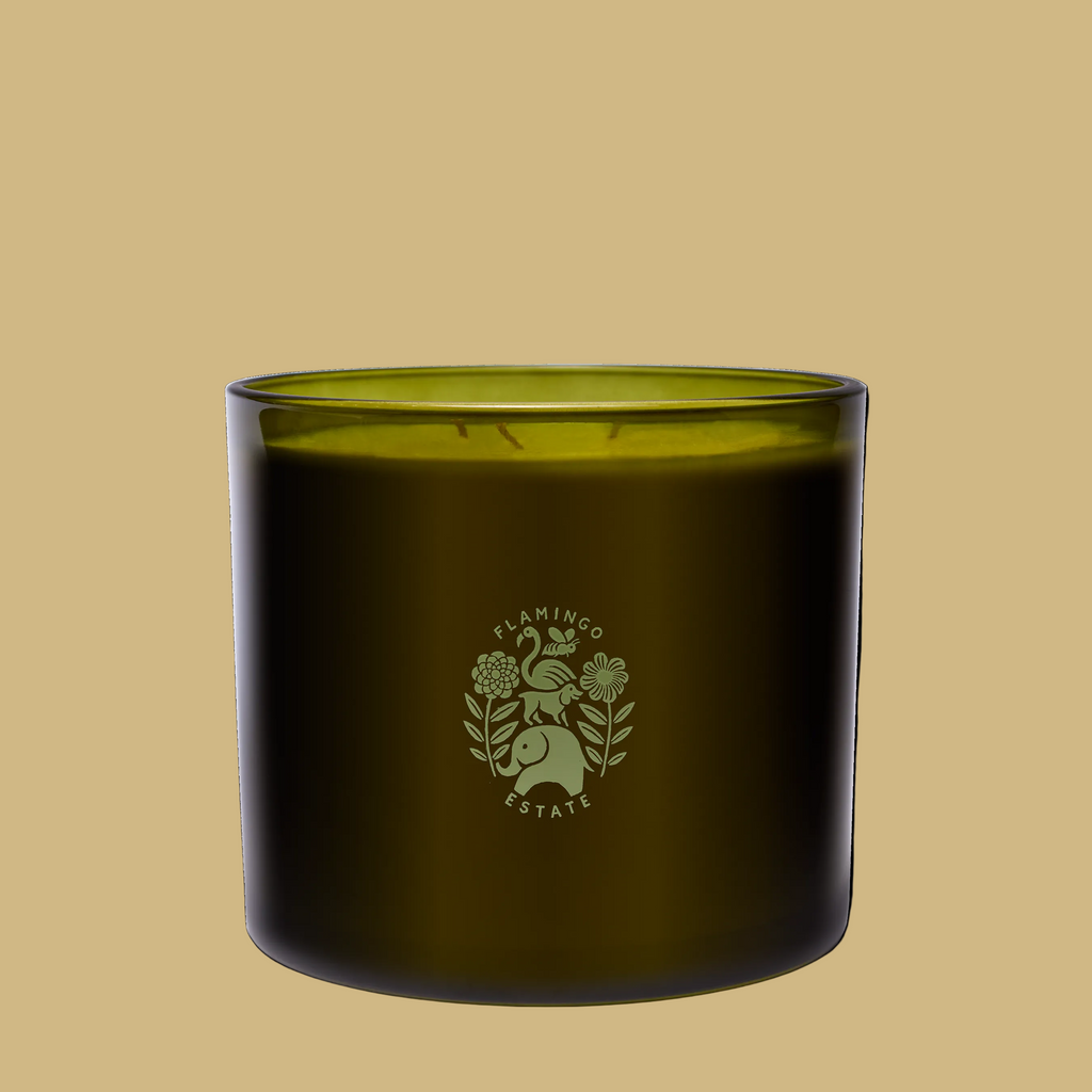 An olive green glass jar candle with a matching green wick and a light green etched logo of a rabbit and flowers reading 'FLAMINGO ESTATE' on the front, set against a plain white background.