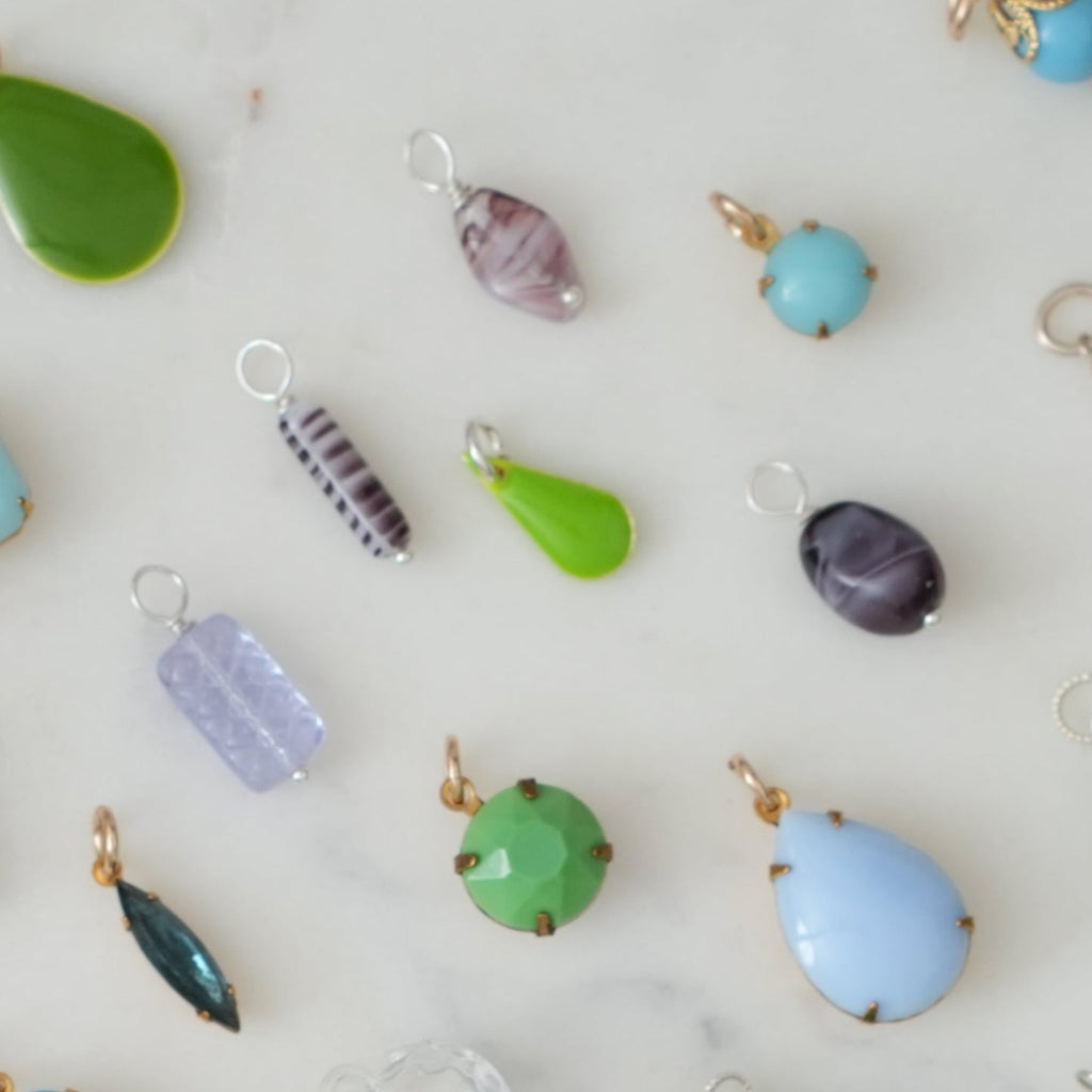 Assorted colorful jewelry charms on a white background