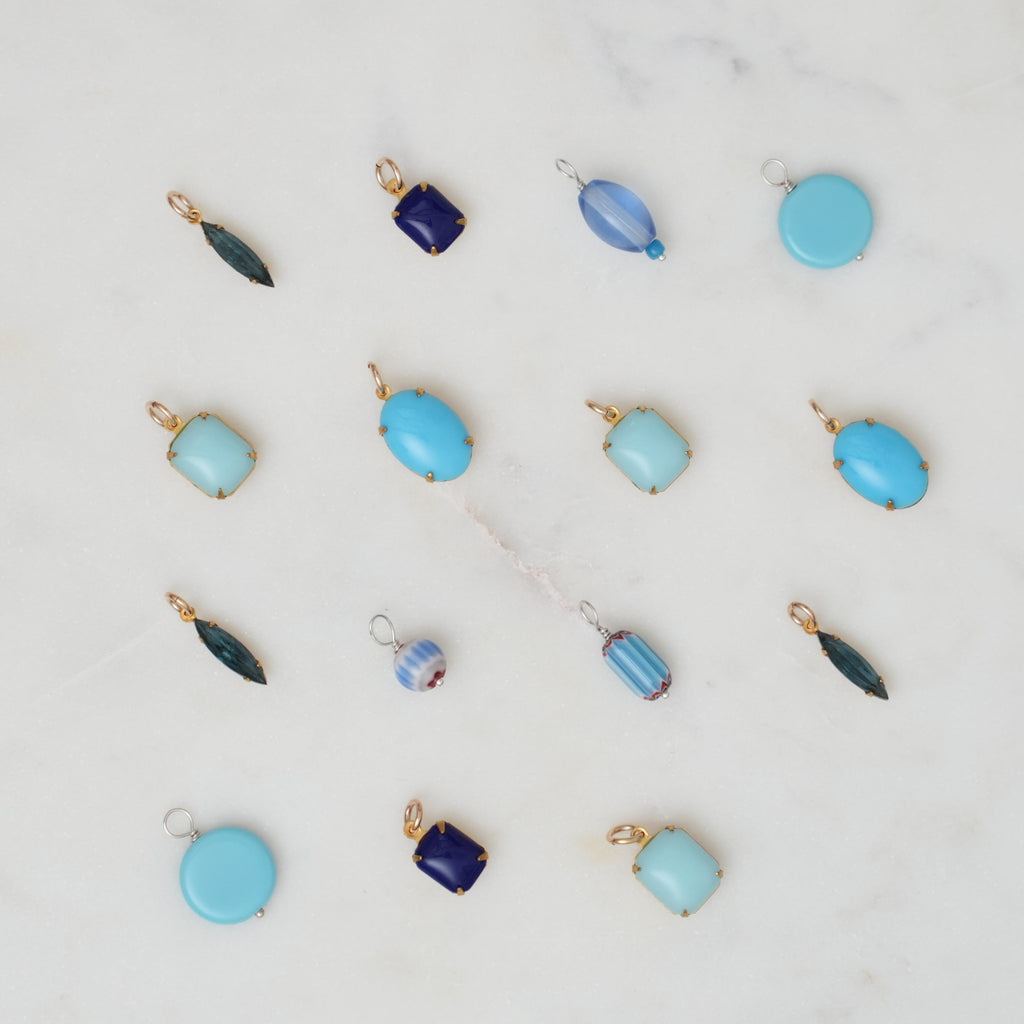Collection of blue and gold jewelry pendants on a light gray background