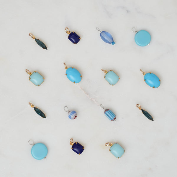 Collection of blue and gold jewelry pendants on a light gray background