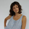 Woman wearing a blue sleeveless top against a white background