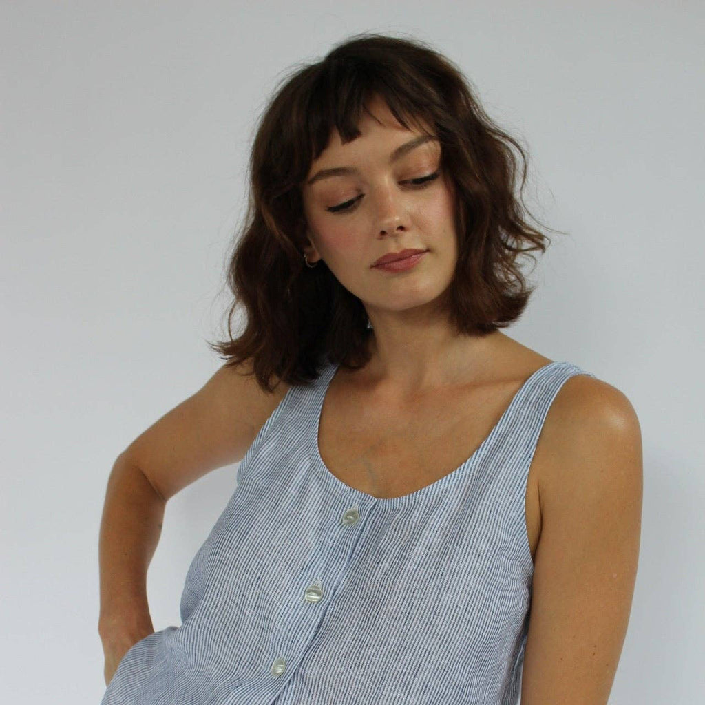 Woman wearing a blue sleeveless top against a white background