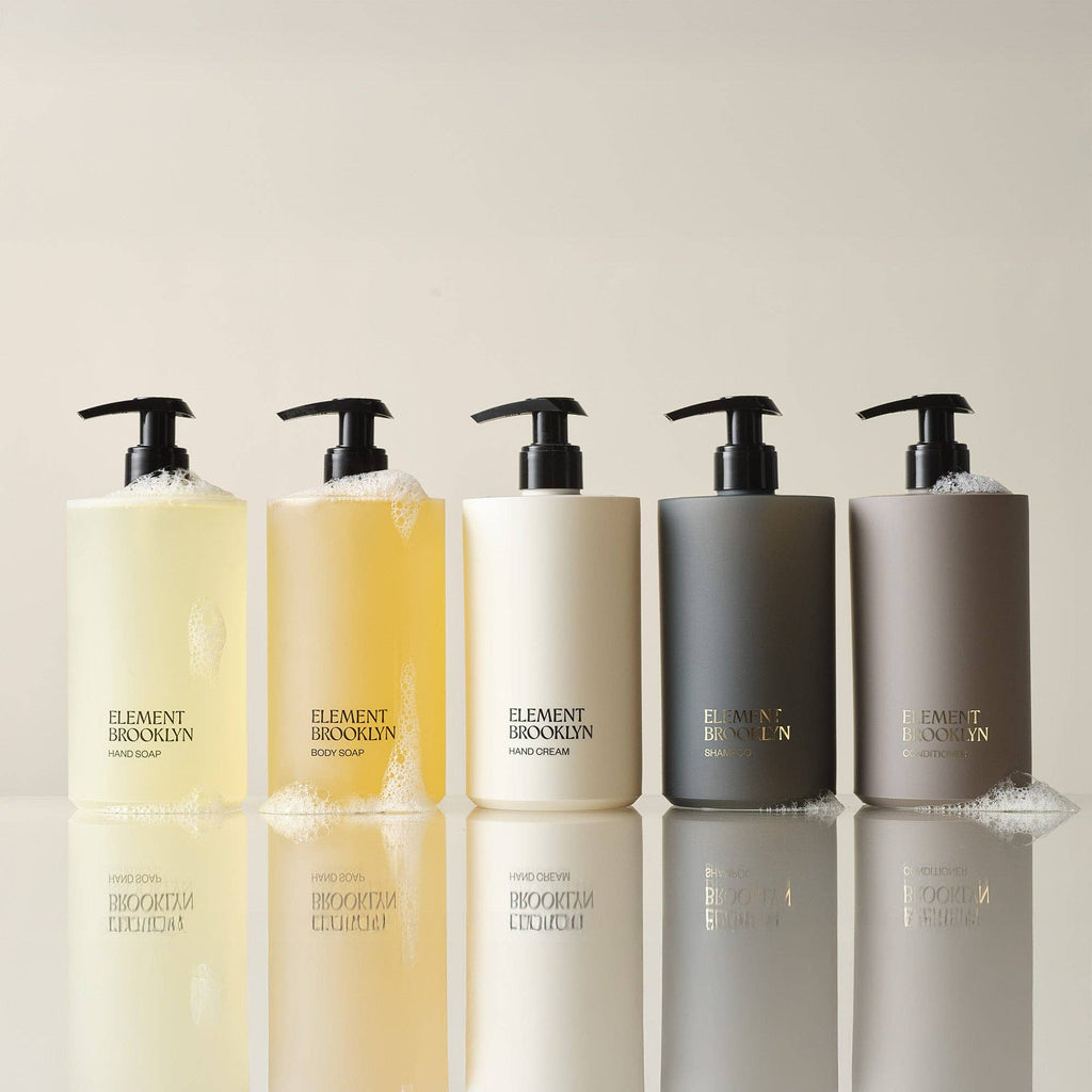 Five bottles of Element Brooklyn products on a reflective surface with a neutral background