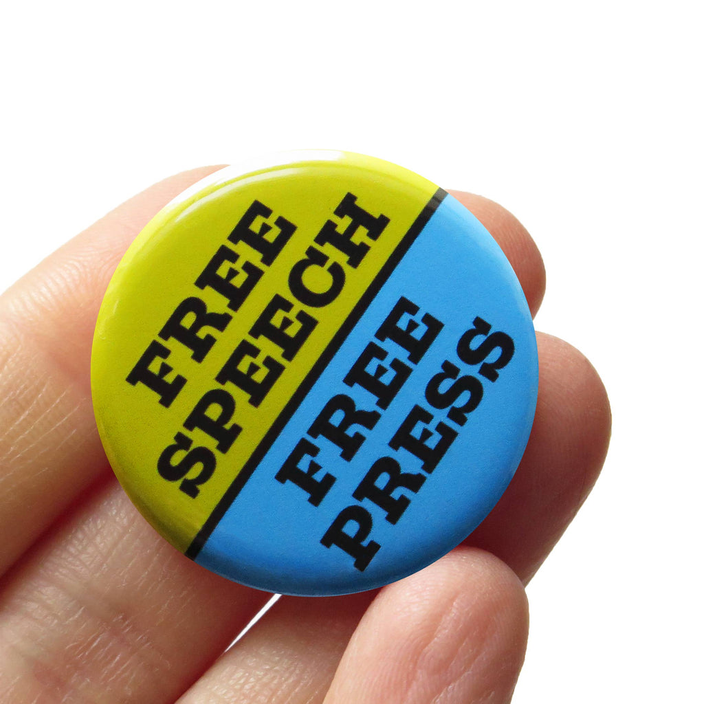 Button badge with 'Free Speech Free Press' text held in a hand