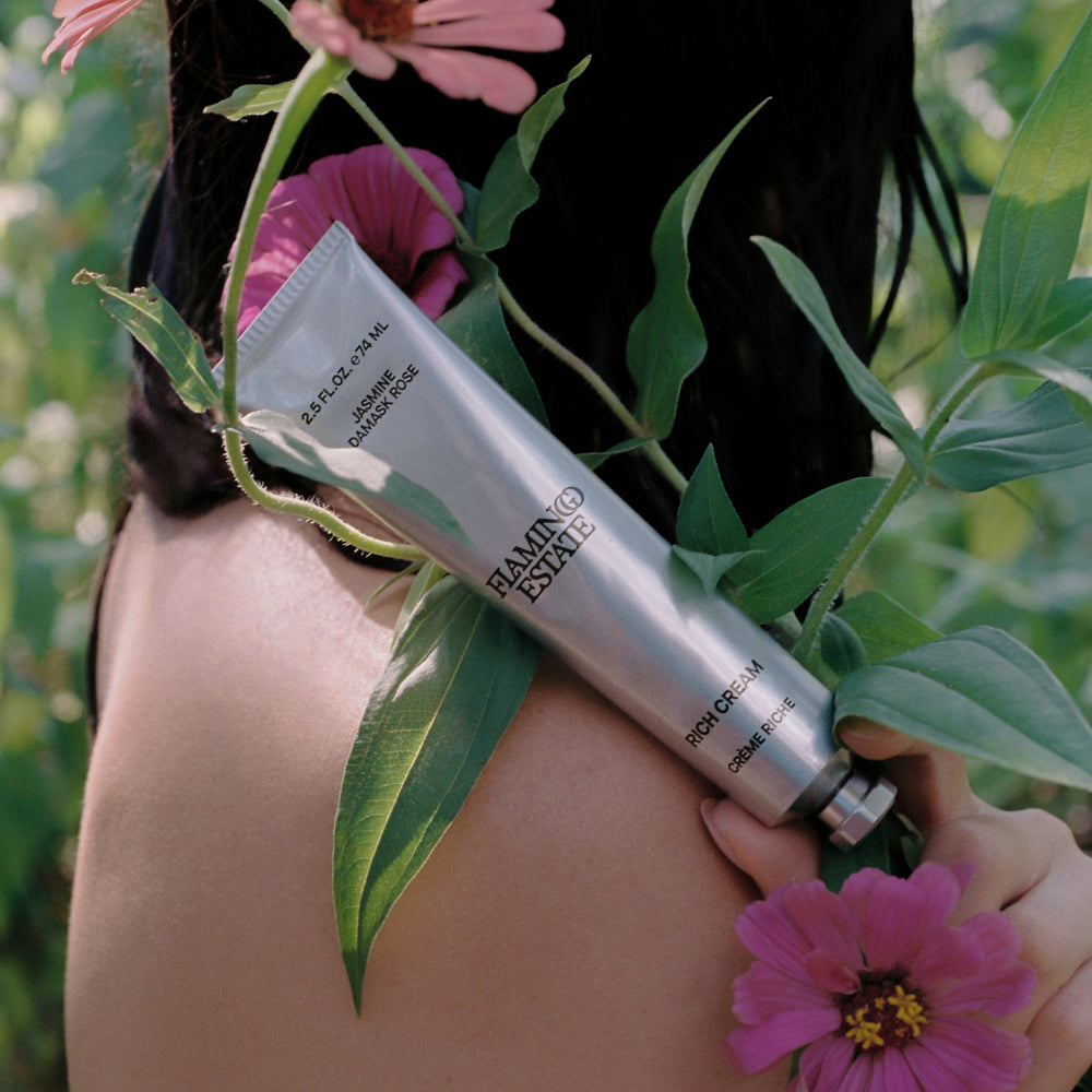 Model holding Jasmine Damask Rose Rich Cream by Flamingo Estate with Flowers