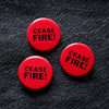 Three red buttons with 'CEASE FIRE!' text on a black denim background