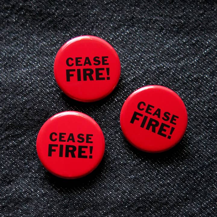 Three red buttons with 'CEASE FIRE!' text on a black denim background