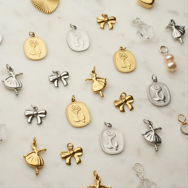 Collection of various gold, silver, and bronze jewelry pendants on a light background