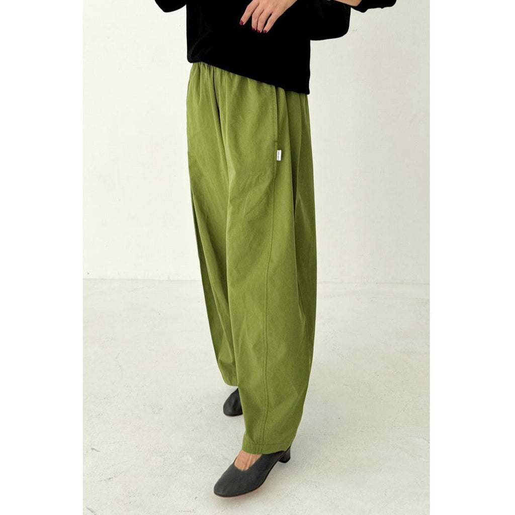 Person wearing green pants and black shoes on a white background