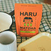 Haru Matcha Oat Milk Latte package on a checkered tablecloth with a white mug and yellow container.