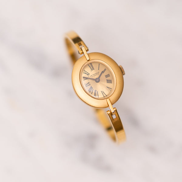 Gold wristwatch with a white background