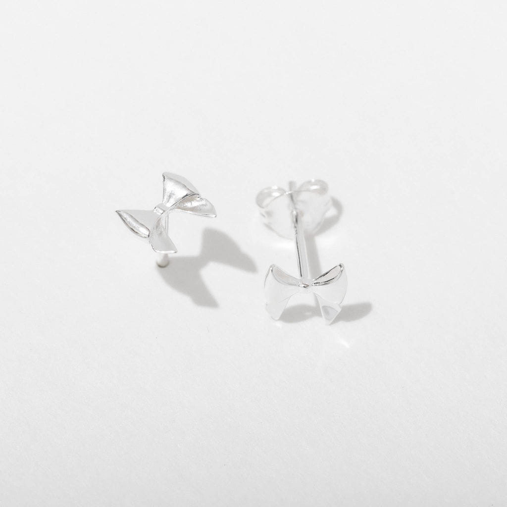 Silver bow-shaped earrings on a light gray background