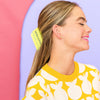 Woman wearing a yellow hair clip with 'Butter' branding against a colorful background