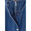 Close-up of a blue denim garment featuring a central silver zipper, metal snap buttons, and contrast white stitching on a plain white background.