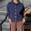 Person wearing "The Club" navy blue cardigan and brown pants standing on steps.
