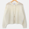 A cream-colored, fuzzy knit cardigan sweater hanging on a wooden hanger with a blue hook against a plain white background. The brand label reads "LE BON SHOPPE"