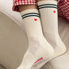 White socks with red hearts and blue stripes worn with red checkered pants on a light background