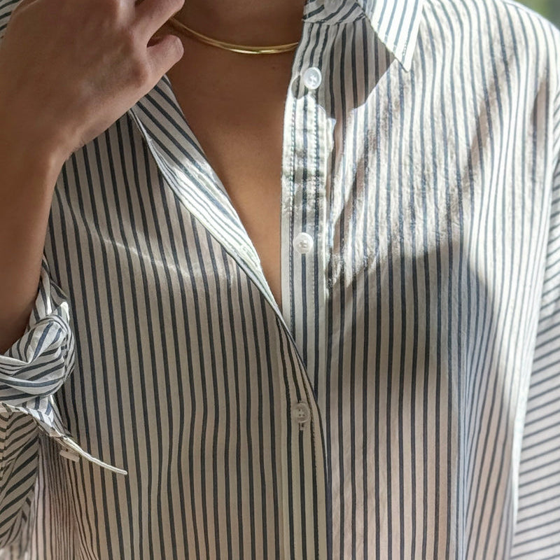 Close-up of a person wearing a striped shirt with a blurred background