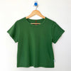 Green t-shirt on a wooden hanger against a white background