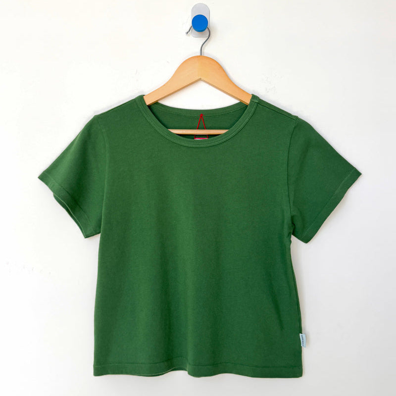 Green t-shirt on a wooden hanger against a white background
