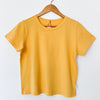 Yellow Le Bon Shoppe t-shirt on a wooden hanger against a white background