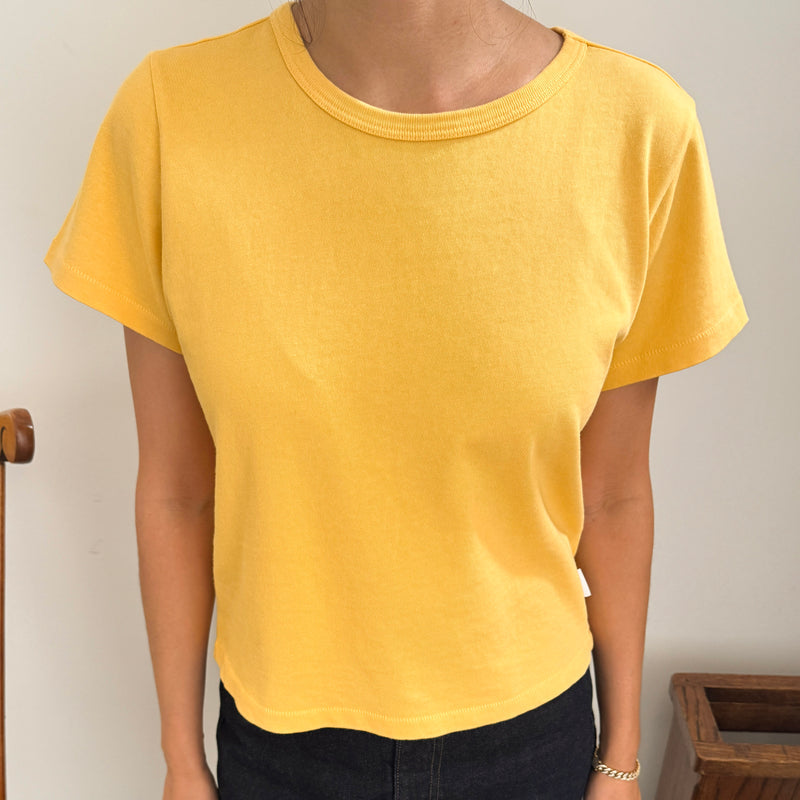 Person wearing a yellow t-shirt against a plain background