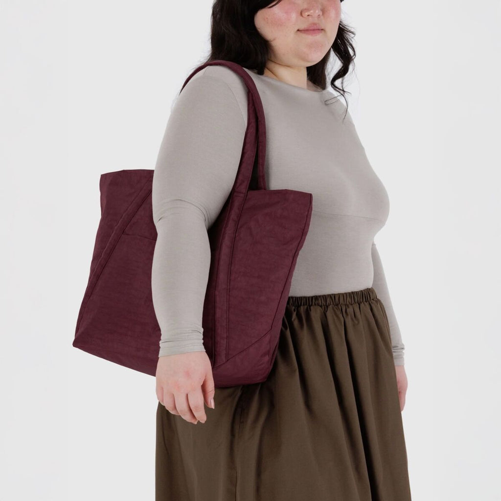 Person wearing a maroon quilted bag on a white background