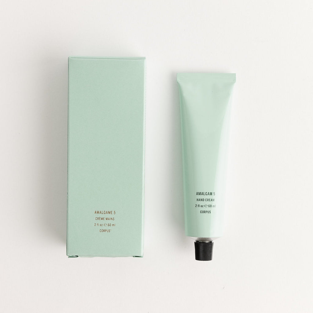 Mint green tube and packaging of Corpus hand lotion on a white background