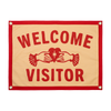 Fabric sign with 'Welcome Visitor' text and a red border on a beige background