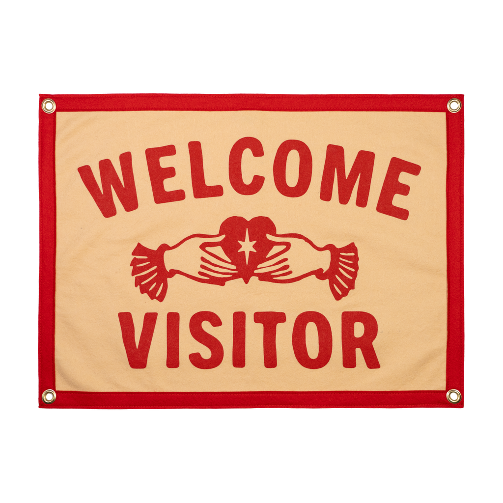Fabric sign with 'Welcome Visitor' text and a red border on a beige background