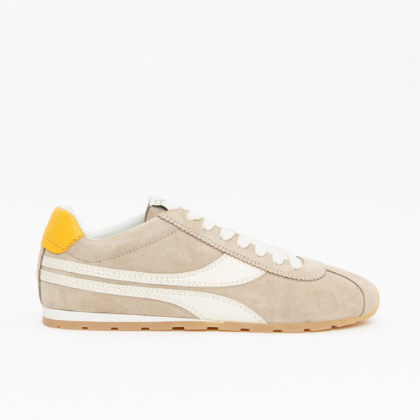 A beige suede low-top sneaker with white leather side stripes, white laces, a yellow heel tab, and a gum sole, shown in profile against a plain white background.