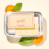 Handmade chocolate bar on a platter with 'Superfine New York' label, surrounded by satsuma mandarin oranges on a light background.