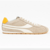 A side-profile view of a beige suede sneaker with white stripes, a white laces, a yellow heel tab, and a tan outsole, shown on a white webpage background with product details on the right.