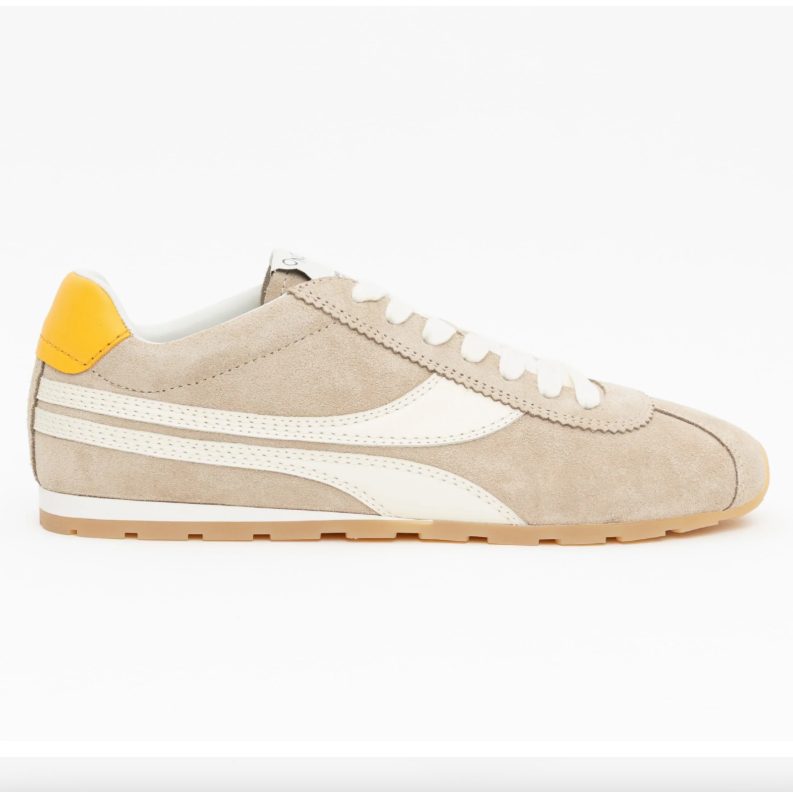 A side-profile view of a beige suede sneaker with white stripes, a white laces, a yellow heel tab, and a tan outsole, shown on a white webpage background with product details on the right.