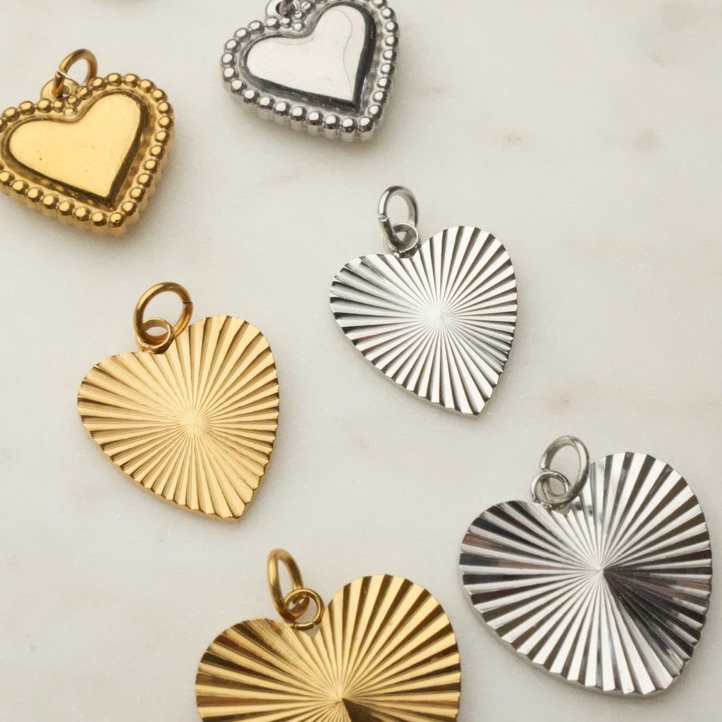 Collection of heart-shaped pendants in gold and silver on a light background