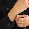 Gold bracelet and ring on a wrist with a black denim jacket background