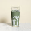 Green glass with white decorative design on a beige background