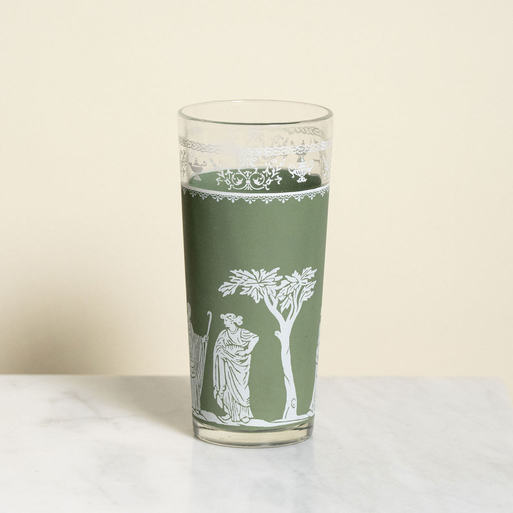 Green glass with white decorative design on a beige background