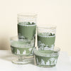 Set of vintage green glass tumblers with white patterns on a white surface