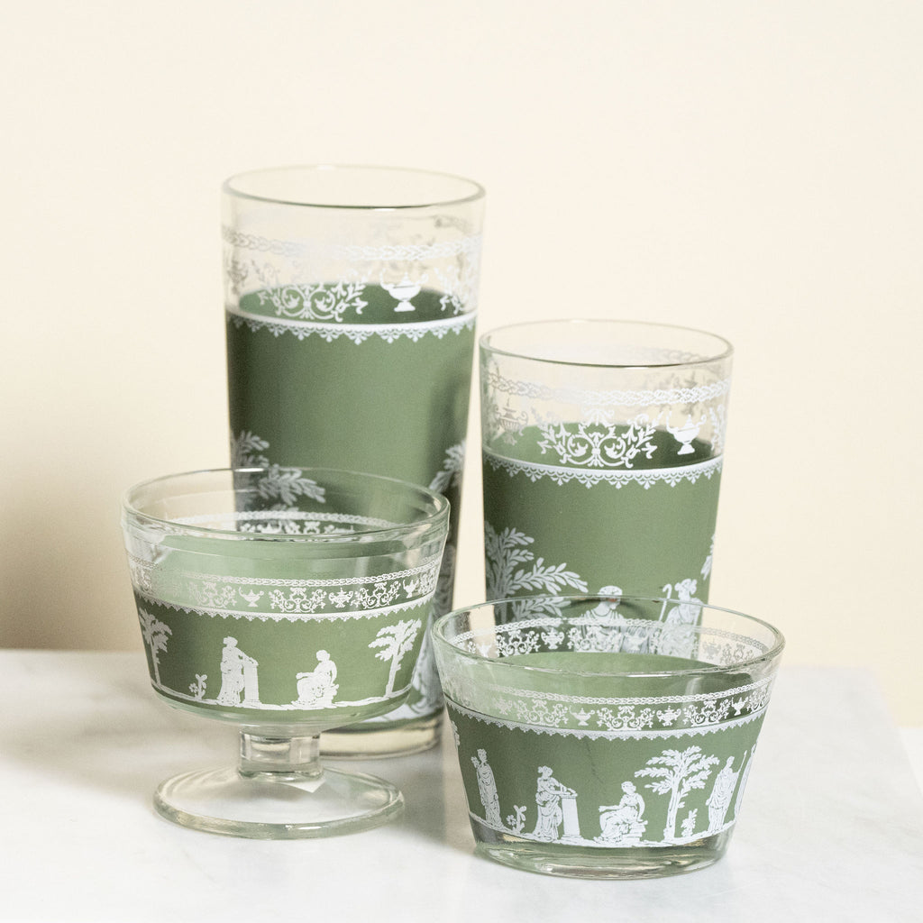 Set of vintage green glass tumblers with white patterns on a white surface