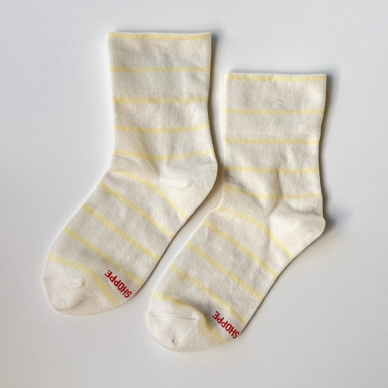 Pair of white socks with yellow stripes on a light gray background